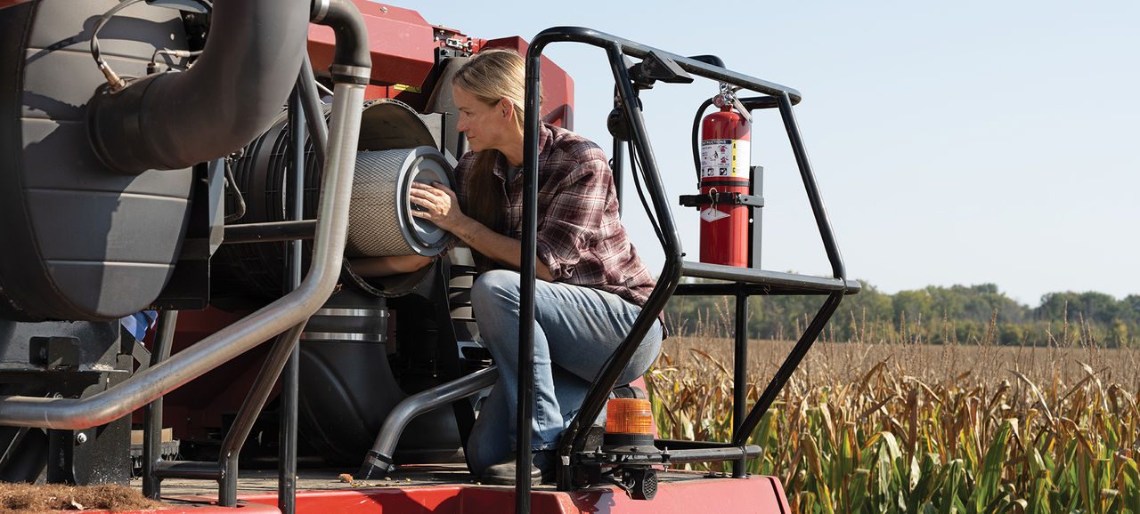 Farmer replacing a filter on a tractor in a corn field